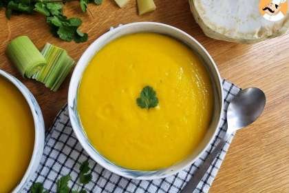 sopa de legumes em uma tigela branca sobre uma toalha quadriculada nas cores branca e azul, ao redor ingredientes da sopa
