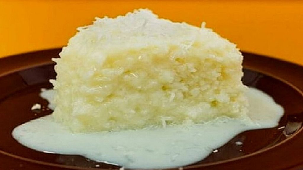 pedaço de bolo de tapioca com cobertura de leite em um prato marrom em um fundo laranja.  