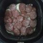 calabresas sobre cebolas cortas em fatias dentro do cesto de da air fryer